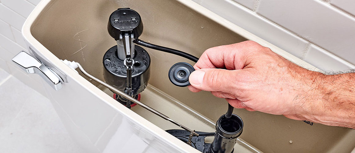 Plumber repairing toilet tank fill valve